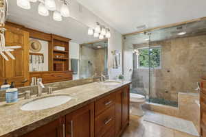 Full bathroom with a stall shower, tile patterned floors, double vanity, and toilet