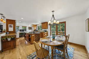 Dining room with light wood finished floors, baseboards, a chandelier, and recessed lighting