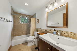 Full bathroom featuring toilet, tile patterned floors, vanity, and shower / tub combo with curtain