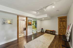 Living area featuring rail lighting, wood finished floors, and baseboards