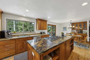 Kitchen featuring open shelves, a sink, stainless steel appliances, brown cabinetry, and a center island