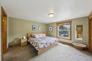 Carpeted bedroom featuring baseboards and a textured ceiling