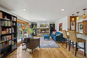 Living room with wood finished floors, recessed lighting, and a stone fireplace