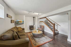 Living area featuring a wood stove, stairway, wood finished floors, and baseboards