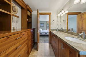 Full bathroom with ensuite bath, double vanity, and tile patterned floors