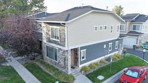 View of side of home with stone siding, covered porch, a yard, and a garage