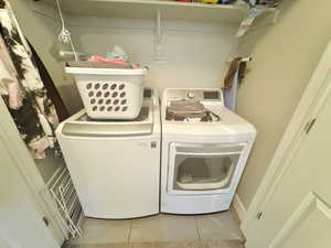Clothes washing area with washer and clothes dryer and tile patterned flooring