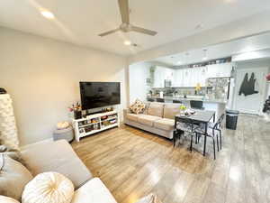 Living room with light wood-style floors, ceiling fan, and recessed lighting