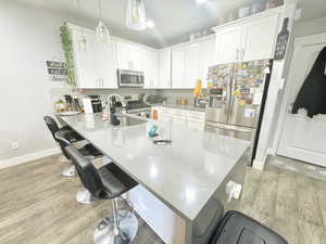 Kitchen featuring appliances with stainless steel finishes, a kitchen breakfast bar, a peninsula, and white cabinets