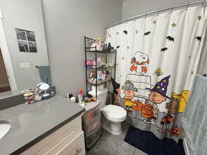 Full bath with tile patterned flooring, vanity, toilet, and a shower with shower curtain