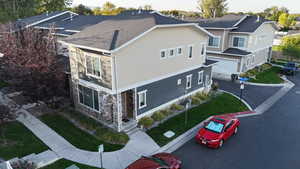 View of property exterior featuring driveway, stone siding, a garage, and a yard