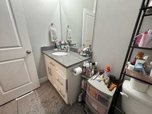 Half bath featuring vanity, tile patterned flooring, and toilet