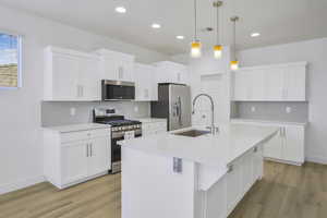 Kitchen featuring appliances with stainless steel finishes, a sink, light wood-type flooring, backsplash, and recessed lighting