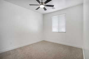 Empty room featuring light colored carpet, baseboards, and ceiling fan