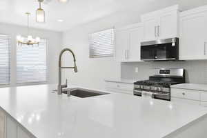 Kitchen featuring stainless steel appliances, a sink, tasteful backsplash, a chandelier, and pendant lighting