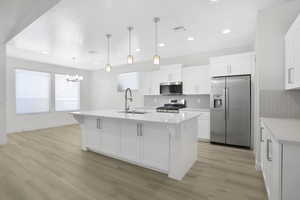 Kitchen featuring stainless steel appliances, a sink, a chandelier, light countertops, and backsplash
