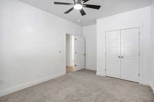Unfurnished bedroom with light colored carpet, a closet, baseboards, and ceiling fan