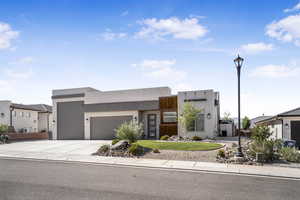 Contemporary house with an attached garage, driveway, stucco siding, and a front lawn
