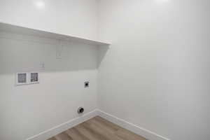Laundry room with hookup for an electric dryer, hookup for a washing machine, light wood finished floors, and baseboards