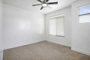 Unfurnished room featuring light colored carpet, healthy amount of natural light, a ceiling fan, and baseboards