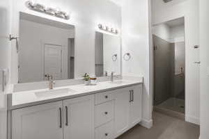 Bathroom with a shower stall, tile patterned flooring, double vanity, and baseboards
