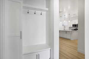 Mudroom with light wood finished floors, a sink, baseboards, and recessed lighting