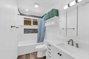 Full bathroom featuring wood finished floors, toilet, vanity, and shower / bath combo with shower curtain