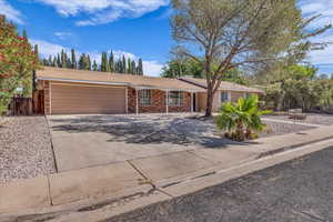 Single story home featuring a garage, concrete driveway, brick siding, and fence