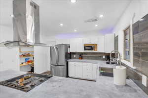 Kitchen featuring exhaust hood, stainless steel appliances, a sink, white cabinets, and decorative backsplash