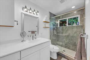 Full bathroom featuring a shower stall, toilet, vanity, and wood finished floors