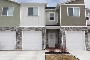 View of property with stone siding, concrete driveway, and board and batten siding