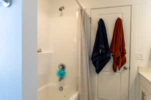 Bathroom featuring shower / bathtub combination with curtain and vanity