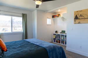 Bedroom with carpet, baseboards, a ceiling fan, and a mountain view