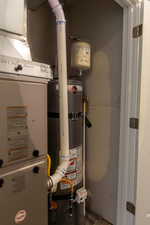 Utility room featuring strapped water heater