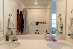 Bathroom featuring a shower with curtain and double vanity
