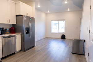 Kitchen with appliances with stainless steel finishes, light wood-style flooring, light countertops, white cabinets, and recessed lighting