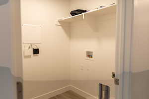 Clothes washing area featuring hookup for a washing machine, hookup for an electric dryer, wood finished floors, and baseboards