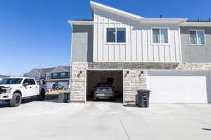View of home's exterior with board and batten siding, stone siding, cooling unit, and an attached garage