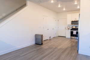 Kitchen featuring stainless steel appliances, white cabinets, light wood-style floors, baseboards, and recessed lighting
