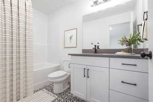 Bathroom featuring toilet, tile patterned floors, vanity, and shower / bath combo