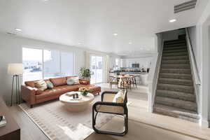 Living room with stairs, light wood-style flooring, and recessed lighting