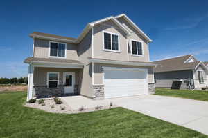 Craftsman-style home with an attached garage, stone siding, concrete driveway, and a front yard