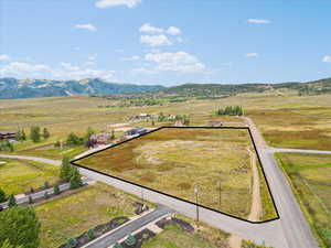Aerial view of sparsely populated area featuring property parcel outlined and a mountain backdrop