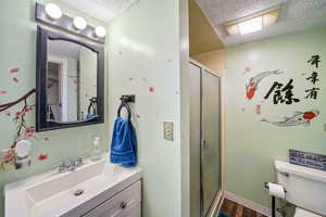 Full bath featuring a textured ceiling, vanity, a stall shower, and wood finished floors