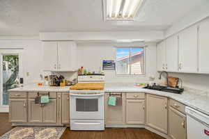 Kitchen featuring white appliances, dark wood-type flooring, light countertops, a textured ceiling, and plenty of natural light