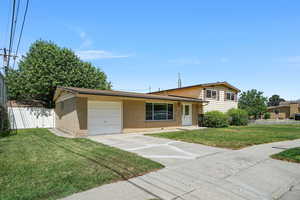 Split level home with a garage, driveway, and brick siding