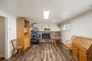 Living area featuring dark wood finished floors, a stone fireplace, and a textured ceiling