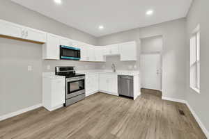 Kitchen featuring appliances with stainless steel finishes, a sink, light countertops, baseboards, and recessed lighting