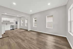 Unfurnished living room featuring a sink, wood finished floors, baseboards, and recessed lighting