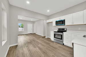 Kitchen with stainless steel range with electric cooktop, light countertops, white cabinets, light wood-style floors, and recessed lighting